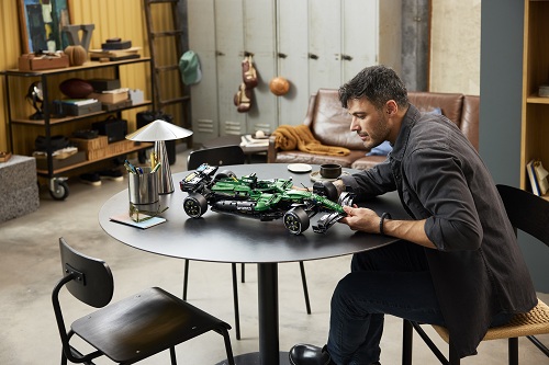 Muž skládající zelené závodní auto z řady LEGO® Technic™.