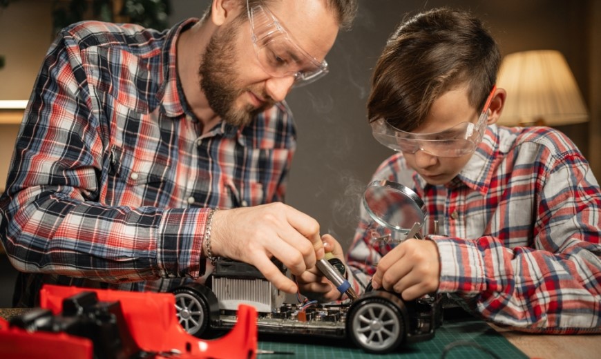 otec a syn pájkou opravují auto na ovládání