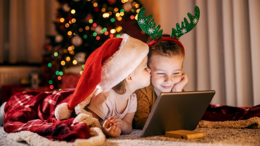 děti sledují tablet před vánočním stromečkem