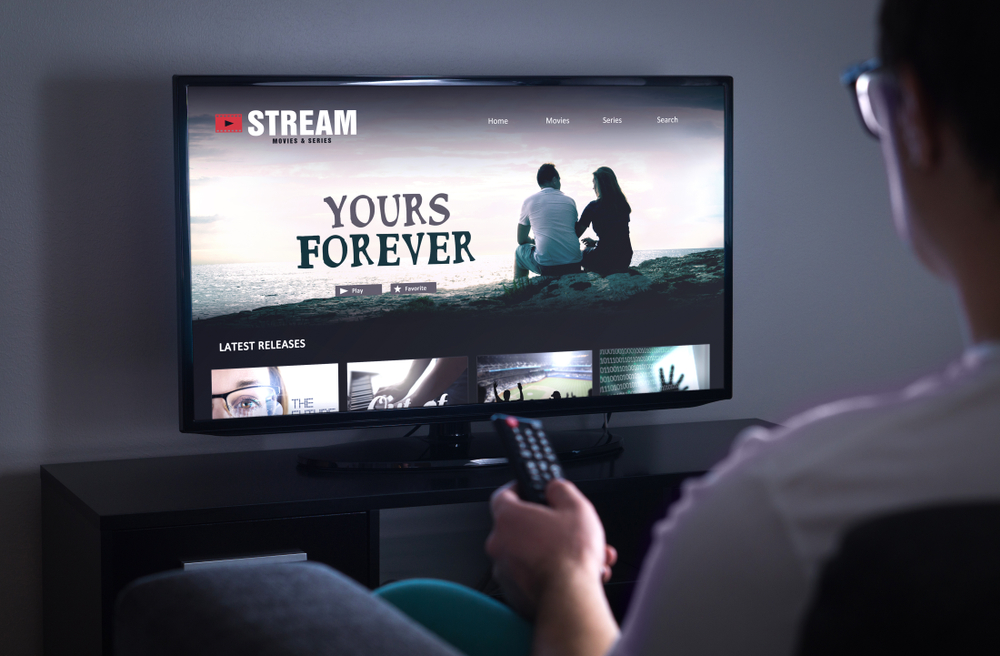 Muž s ovladačem vybírá pořad na Netflixu