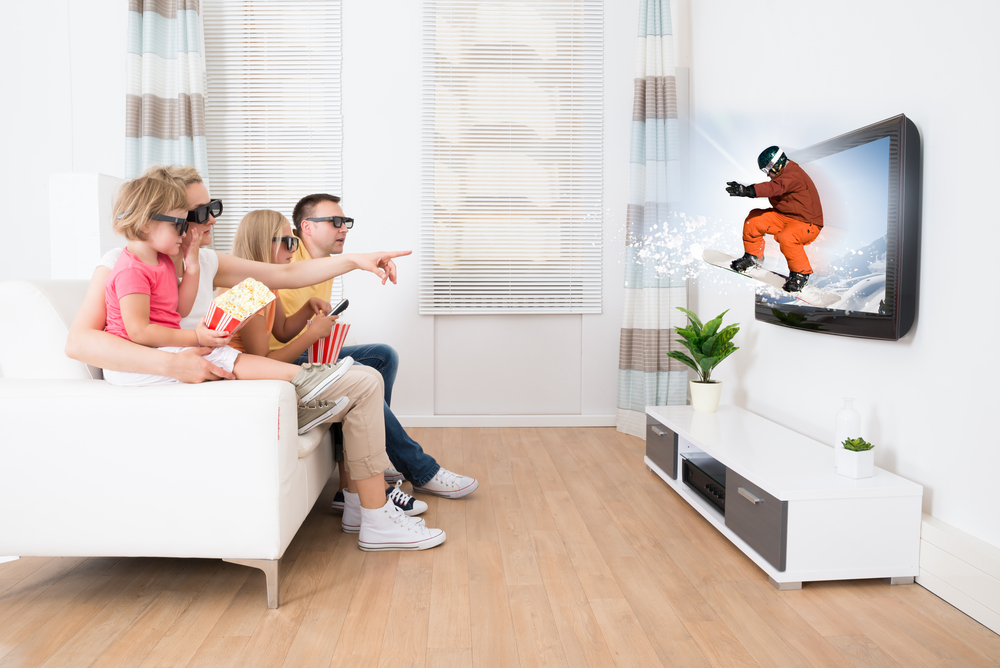Rodina sedí na gauči a sleduje snowboardistu v televizi