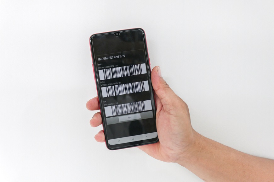 V ruce je mobilní telefon s IMEI kódem