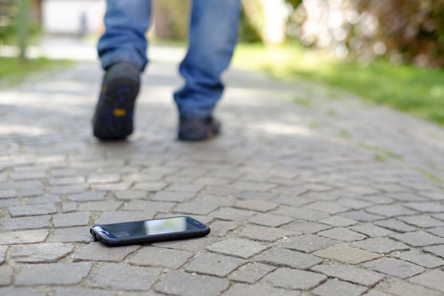 Muž ztratil telefon, ten leží na chodníku a muž dále pokračuje v cestě