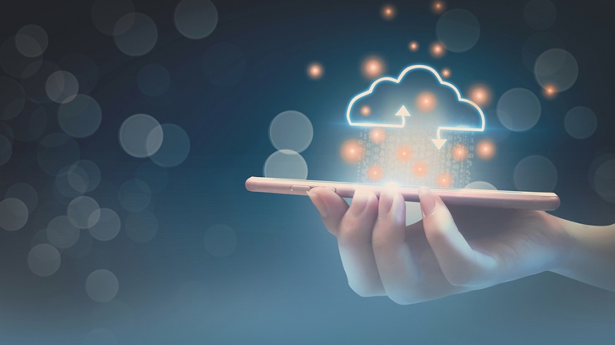 Jak přenést data do nového telefonu Ženská ruka drží v ruce mobilní telefon a nad ním se nachází ilustrace přenosu dat pomocí Cloudu