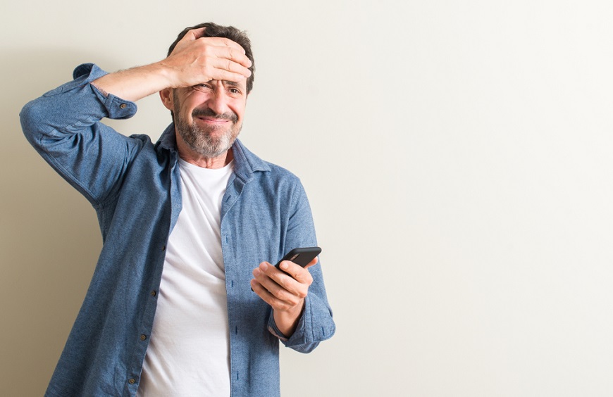 Jak odblokovat telefon? muž se drží za hlavu a v druhé ruce má mobilní telefon