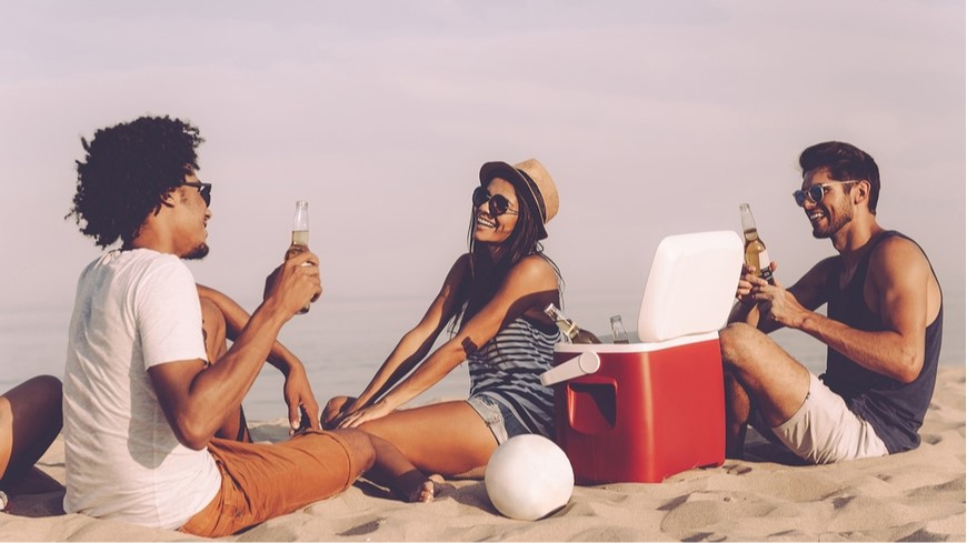 Vybíráme ledničku na cesty dva muži s ženou sedí na pláži a popíjí drink vychlazený v absorpční lednici