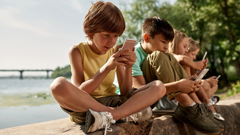 Mladí kluci hrají venku hry na svých mobilních telefonech