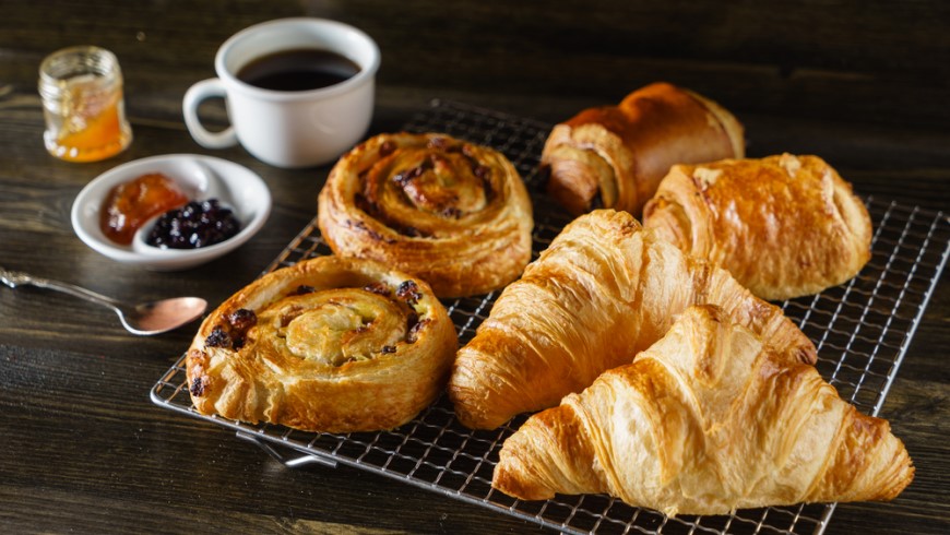 Co (ne)patří do ledničky? Croisant a šneci na mřížce. Vedle marmeláda a káva v šálku.