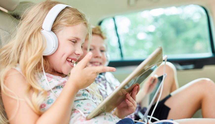 Jak vybrat tablet? děti sedí v autě se sluchátky na uších a tabletem v ruce