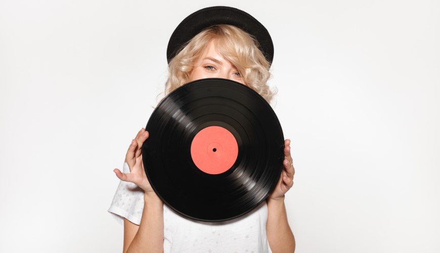 dívka s kloboukem drží vinylovou desku před svým obličejem