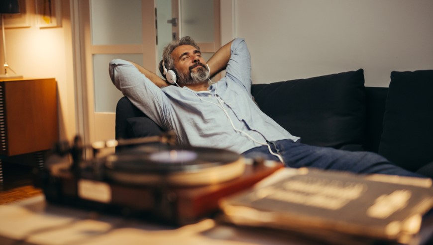 muž se sluchátky na hlavě poslouchá vinylovou desku