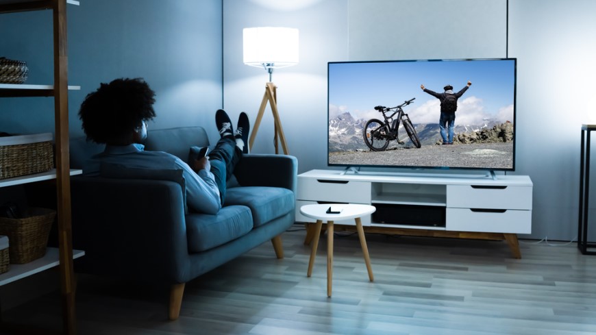 muž sleduje tv pořad z gauče