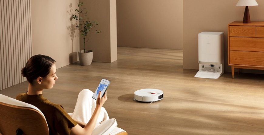 Jak vybrat vysavač? Žena pomocí mobilní aplikace ovládá robotický vysavač se stanicí