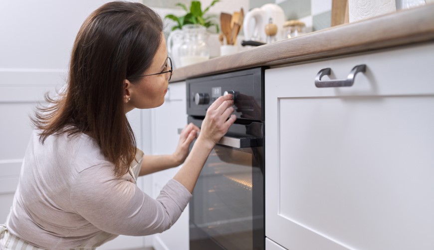 Co znamenají symboly na troubě? žena ovládá troubu pomocí knoflíků