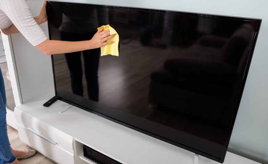 Jak vyčistit televizní obrazovku? žena čistí televizi ručně hadříkem