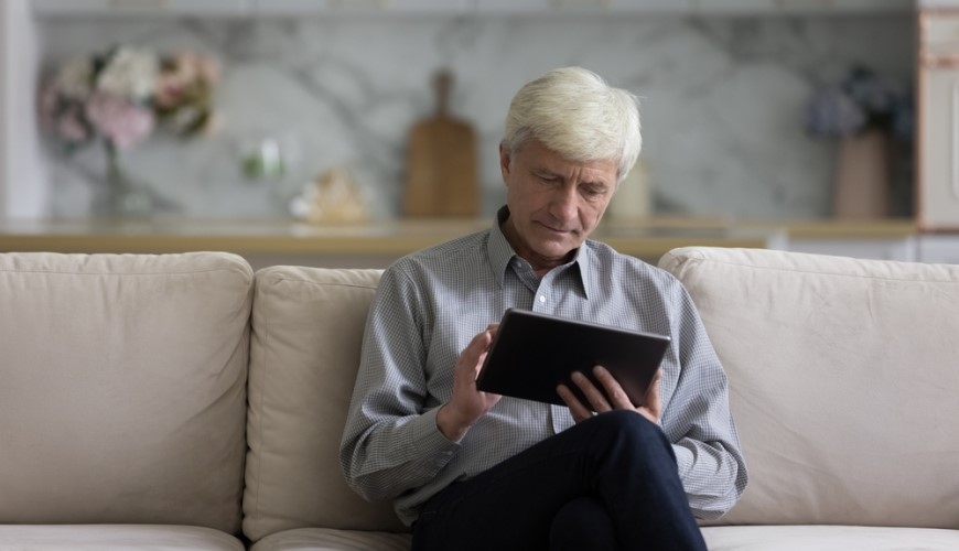 Jak vybrat tablet? starší muž sedí na pohovce a pracuje na tabletu