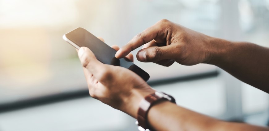 Jak aktualizovat Android: Kompletní průvodce a užitečné rady Mužské ruce drží mobilní telefon. Pravá ruka se ukazováčkem dotýká displeje.
