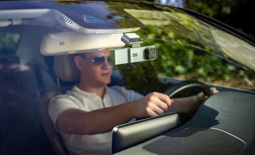 Muž sedí za volantem a za zpětným zrcátkem má umístěnou autokameru.