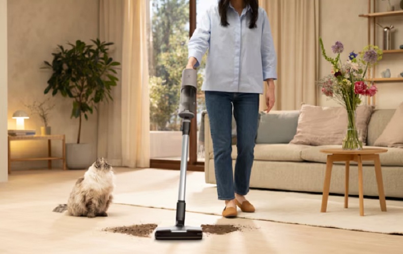 Žena vysává vysavačem Electrolux 600 rozsypanou hlínu z květináče. Vedle ní sedí na zemi kočka 