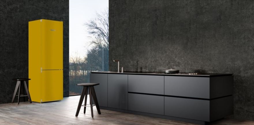 žlutá lednice Liebherr v černé moderní kuchyni. Za oknem podzimní zatažené počasí
