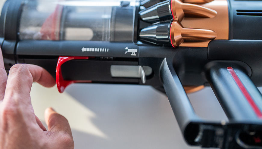 Recenze: Tyčový vysavač Dyson V16 Piston Animal Submarine™ – Expert na podlahy 3 v 1 Záběr na červenou páčku tyčového vysavače Dyson V16 Piston Animal Submarine™