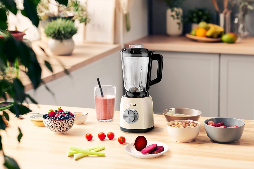 ETA Storio: Styl do každé kuchyně Béžový stolní mixér ETA Storio na dřevěné kuchyňské lince obklopený čerstvým ovocem, zeleninou a hotovým smoothie