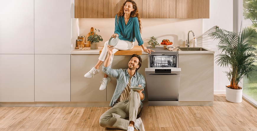 Žena sedí na kuchyňské lince, kde je zabudovaná myčka Gorenje z modelové řady G600. Muž sedí na podlaze.