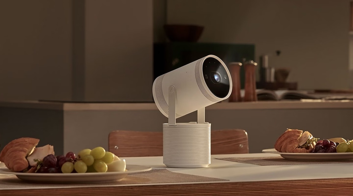Lifestylová kolekce Samsung: Designové televizory a soundbary, které zkrášlí váš domov Projektor Samsung The Freestyle stojí na stole mezi talíři s jídlem, na pozadí je kuchyňská linka