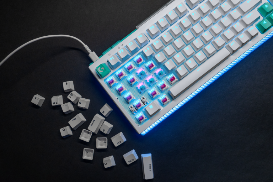 Bílá klávesnice Logitech G512 X s odkrytou částí spínačů, vedle klávesnice ležní hromádka keycapů