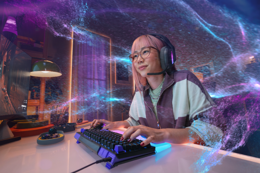 Žena hraje na klávesnici Logitech G512 X, kolem jsou duhové vlny odpovídající barvám podsvícení klávesnice