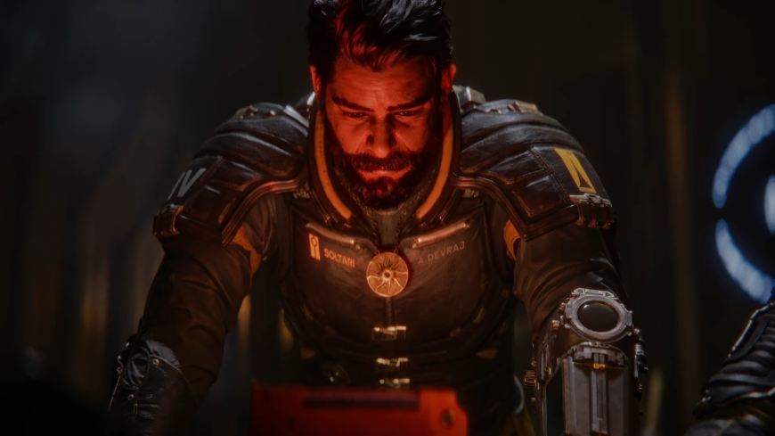 Saros: Zachovej si chladnou hlavu v žáru boje na Carcose Arjun Devraj se skloněnou hlavou ozářenou červeným světlem, screenshot z traileru