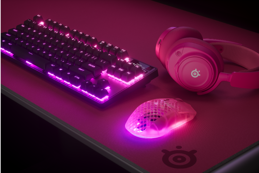 Nová myš SteelSeries Aerox 3 Wireless Gen 2: Vylepšená generace je tady Myš SteelSeries Aerox 3 Wireless Gen 2 v provedení MagentaHaze leží na stole vedle headsetu a klávesnice SteelSeries