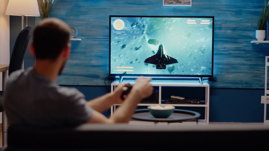 Nejčastější televizní zkratky a technologie Muž hraje hru na televizi s podsvícením