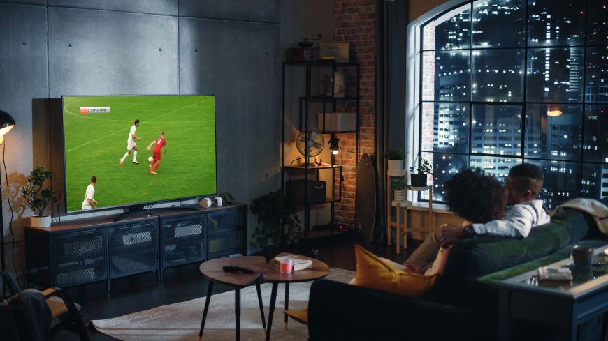 Nejčastější televizní zkratky a technologie Pár sleduje fotbalový zápas na televizi v obývacím pokoji