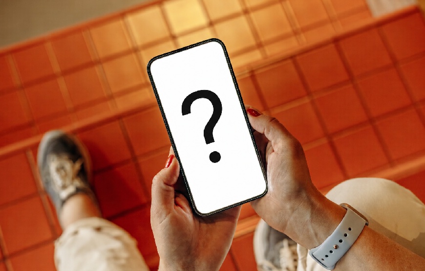 Vše o mobilech: 10 otázek, na které se ptáte nejčastěji Displej telefonu s otazníkem. Telefon někdo drží v rukou. V pozadí je podlaha s kachličkami.