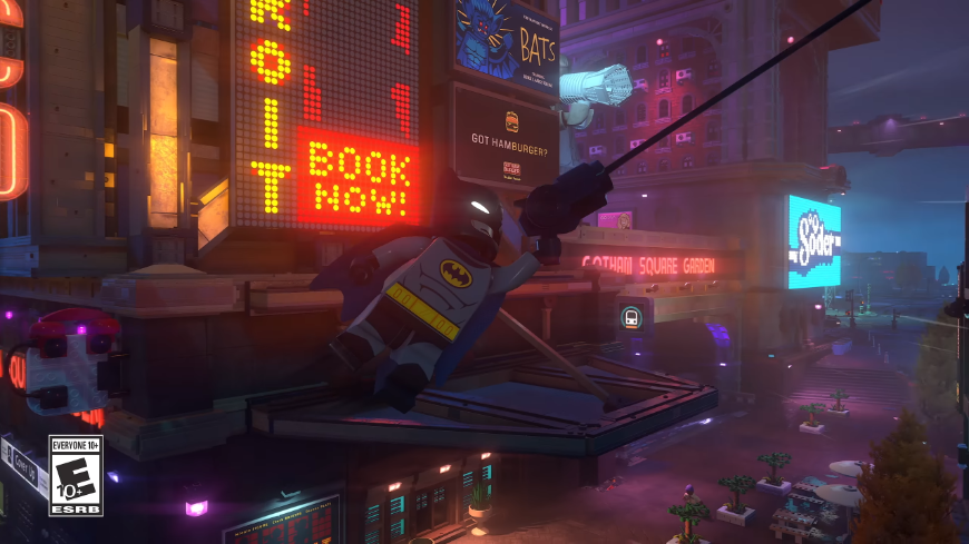 LEGO Batman se houpe na provazu, na pozadí je město s neonovými nápisy