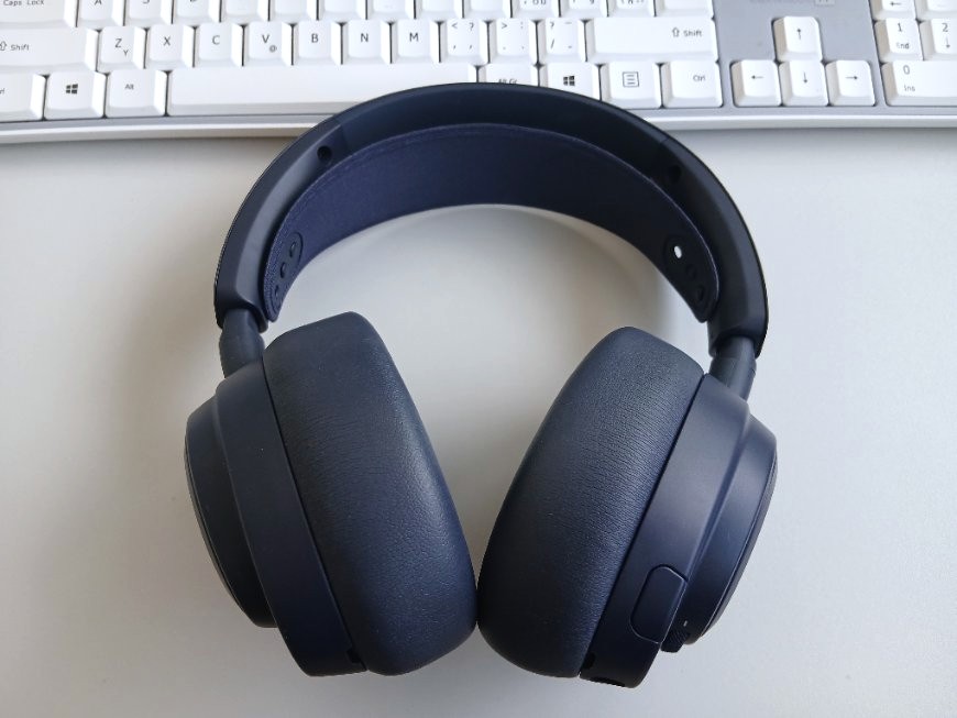 Arctis Nova Pro Omni leží na stole, za ním je bílá klávesnice