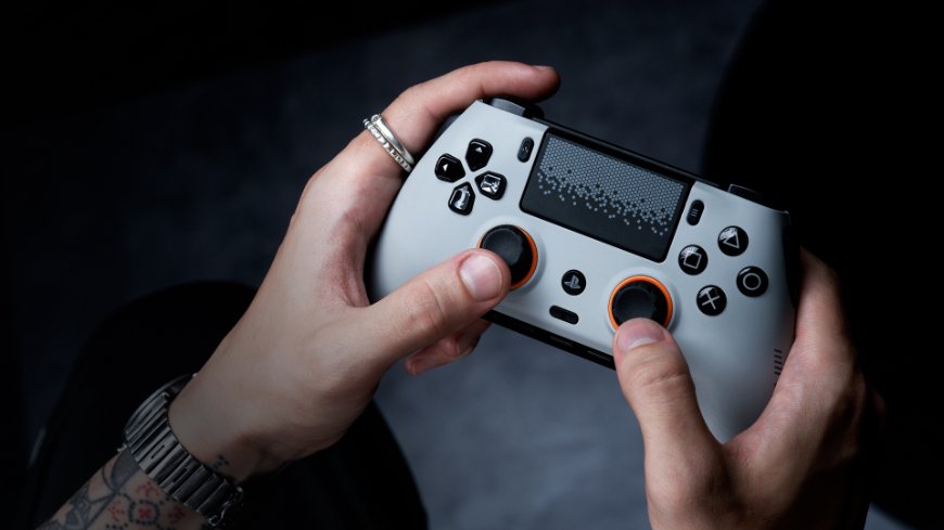 Ruce drží bílý ovladač Scuf Omega s oranžovými detaily