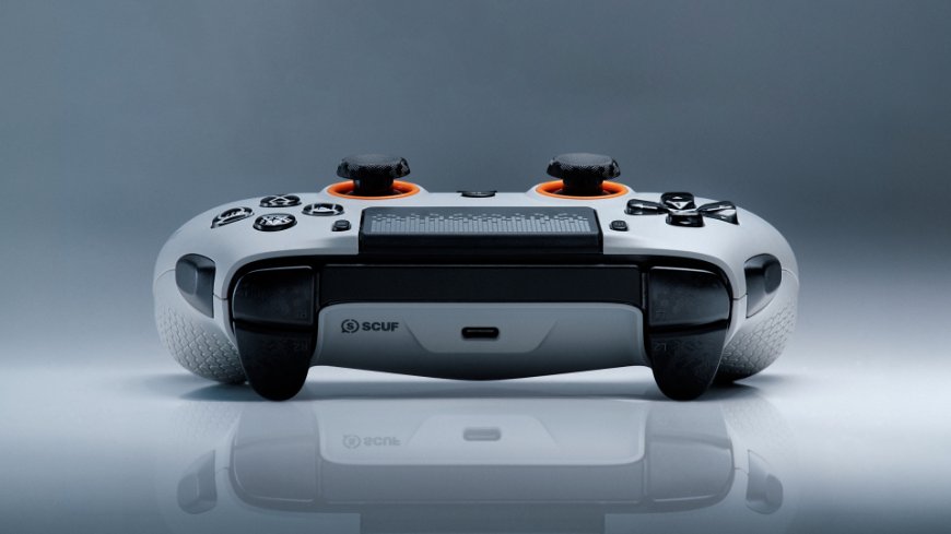 Herní ovladač Scuf Omega pro PS5 v bílém provedení s oranžovými detaily leží na stole
