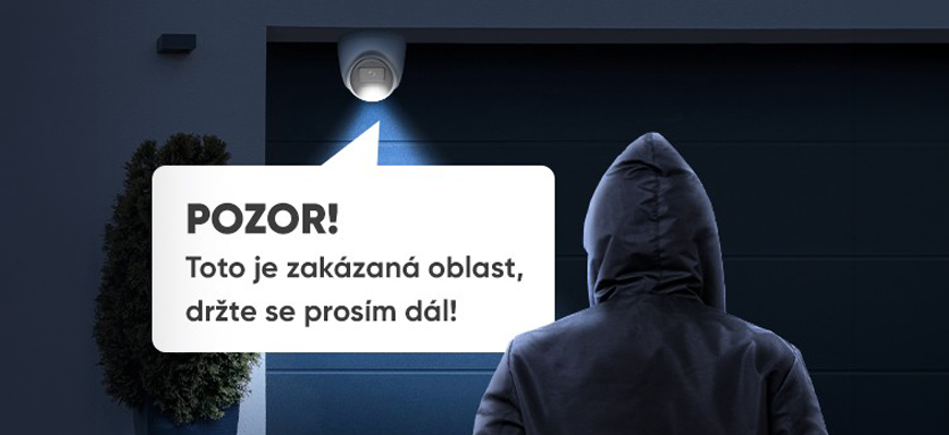 HiLook Smart Hybrid Light: Barevné noční vidění pro domácnosti i firmy Muž v mikině s kapucí před garáží, Nad vraty svítí kamera HiLook a znázorňuje hlasové upozornění.