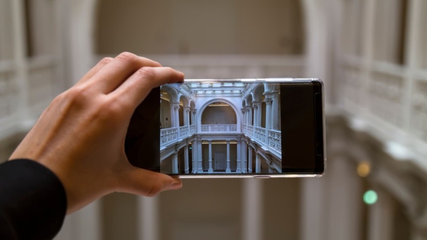 Jak pořídit dobré fotky mobilem? Symetrická kompozice v praxi – fotografování architektonických prvků – sloupořadí a klenutých oblouků – smartphonem v mužské ruce.