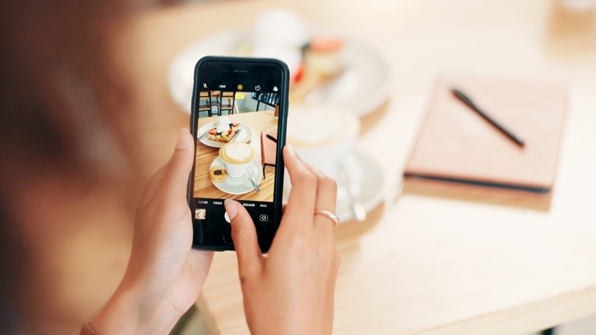 Jak pořídit dobré fotky mobilem? Žena brouzdající ve fotoaplikaci mobilního telefonu ve snaze pořídit perfektní snímek jídla