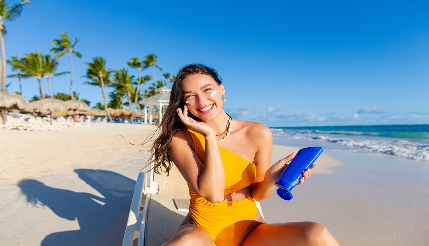 Usmívající se žena na pláži s SPF krémem