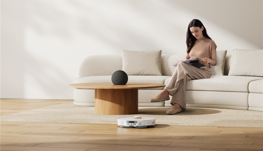 Žena si čte na gauči a před ní vysává obývací pokoj robotický vysavač Xiaomi Robot Vacuum H50 Pro