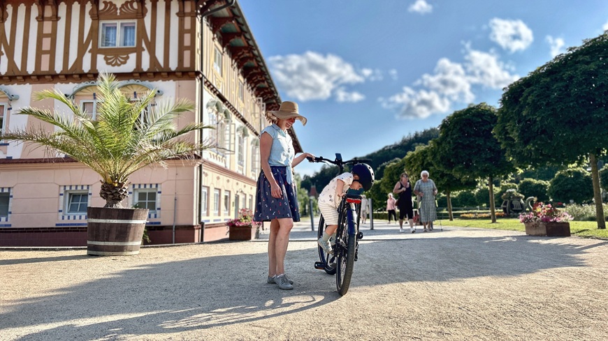 Recenze: Elektrokolo GoGEN Aspen MX 720 se postará o to, aby vaše cyklochoutky nic nebrzdilo Batole snažící se nasednout na elektrokolo GoGEN Aspen MX 720 v šedo-černém provedení uprostřed lázeňské kolonády