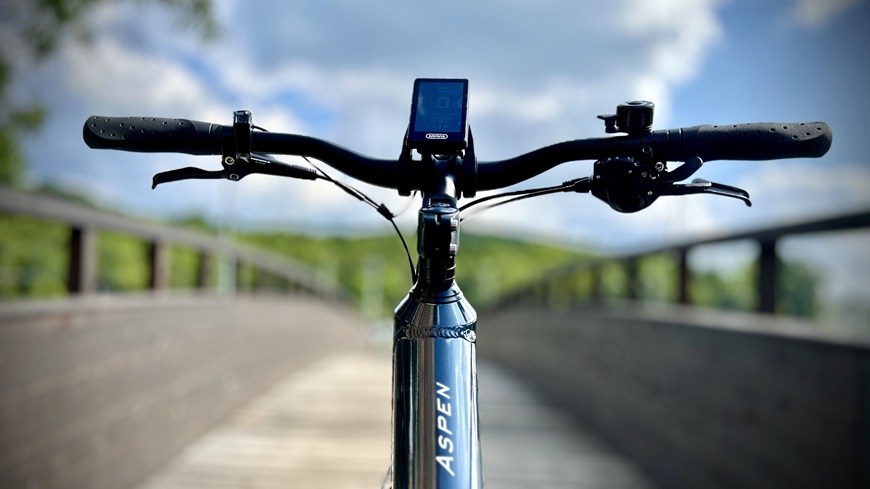 Recenze: Elektrokolo GoGEN Aspen MX 720 se postará o to, aby vaše cyklochoutky nic nebrzdilo Detail řídítek a ovladače elektrokola GoGEN Aspen MX 720 uprostřed dřevěné lávky