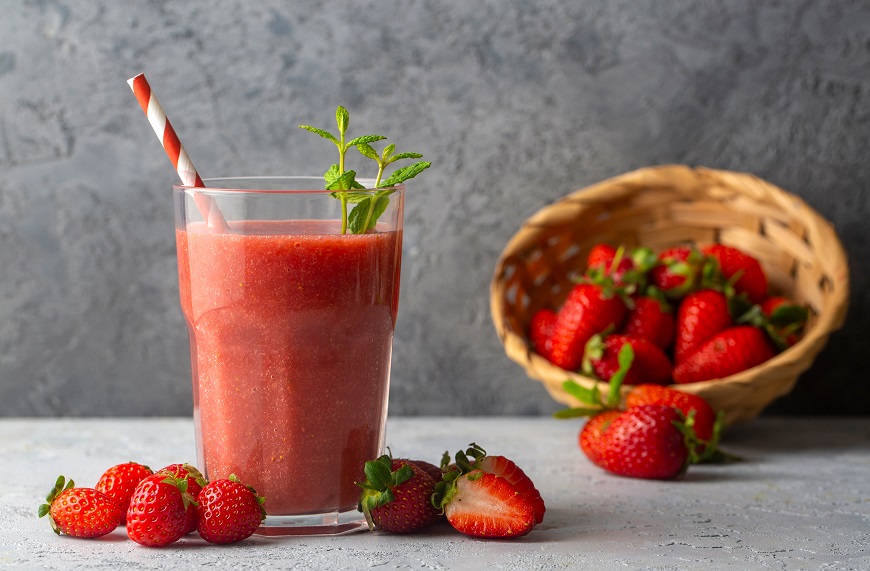 Nejlepší pomocníci na léto? Vychytávky Gorenje pro prázdninovou pohodu jahodove smoothie ve sklenici s brčkem, vedle jsou jahody