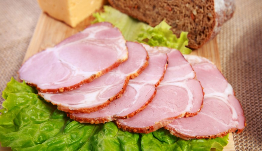 Domácí šunka na dřevěném prkýnku s listovým salátem