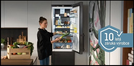 žena stojí u otevřené lednice Liebherr a uklada poktraviny, na boku obrazku je videt ikona 10lete zaruky