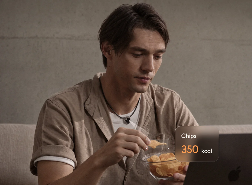 AI náhrdelník ODYSS N1 na krku muže, který konzumuje brambůrky
